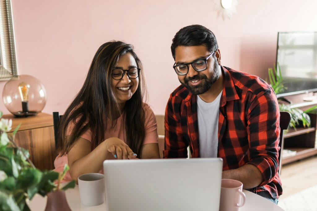 latino or indian man and woman couple use their laptop in the living room to make video calls video